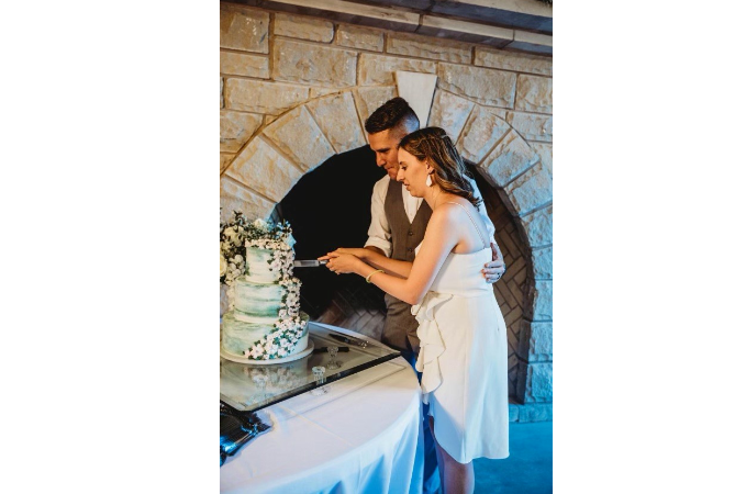 "Cutting Cake In Front Of Rock Fireplace In Pavilion"