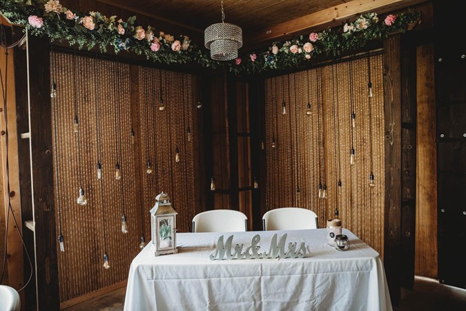 "Bride & Groom's Table With Flowered Arbor & Edison Lights"