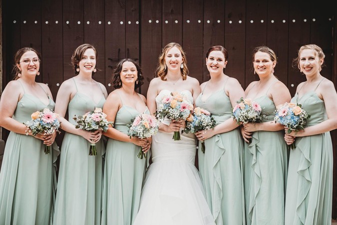 "Bride & Bridesmaids In Front Of Doors Of Enclosed Building"