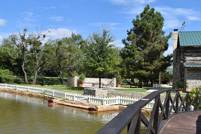 "Rock Bench Along Water's Edge and Fire Pit In Background"