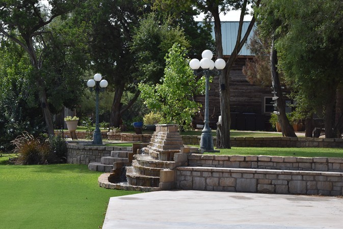 "Flower Pots on Small Patios & Sign Post Tree Beyond Waterfalls"